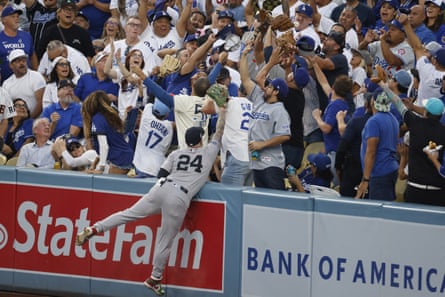 yankee player dives into the stands to catch a ball as Dodger fans look thrilled