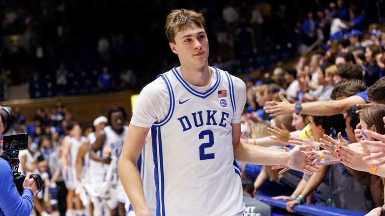 Duke's Cooper Flagg (2) high-fives fans after NCAA college basketball...