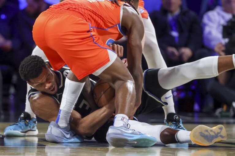 Milwaukee Bucks forward Giannis Antetokounmpo (34) wrestles for a loose ball with Oklahoma City Thunder guard Cason Wallace (22) during the first half of the championship game in the NBA Cup basketball tournament Tuesday, Dec. 17, 2024, in Las Vegas. (AP Photo/Ian Maule)