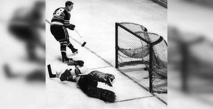 Bill Mosienko flips the puck past Lorne Anderson for his hat trick goal on March 23, 1952. Anderson's glove, beside Mosienko's skate, flew off in his attempt to make the save.