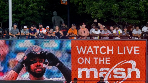 Fans stand Aug. 8, 2023, above a digital ad sign for MASN at Oriole Park at Camden Yards. (Karl Merton Ferron/Staff)