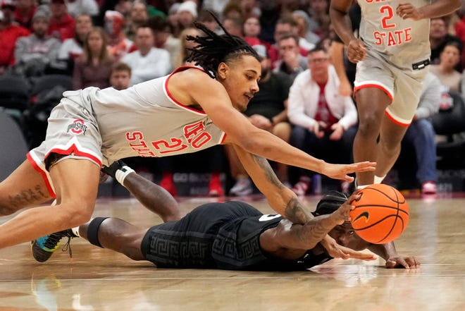 Ohio State forward Devin Royal, top, and Michigan State forward Coen Carr, right, dive for a loose ball in the first half of an NCAA college basketball game Friday, Jan. 3, 2025, in Columbus, Ohio.