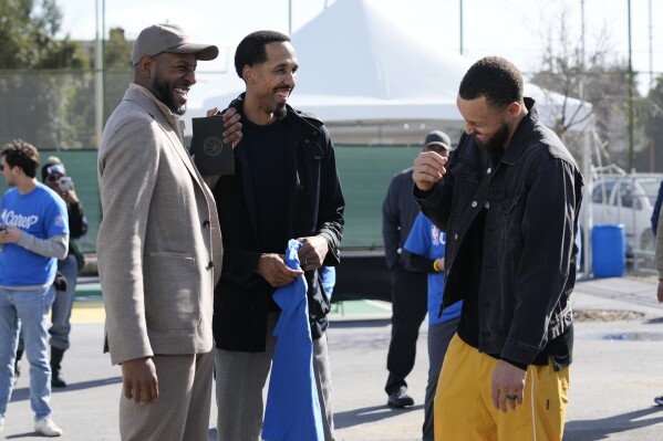 Stephen Curry, right, talks to his ex-teammates Andre Igoudala and Shaun Livingston during a visit to East Oakland Pride Elementary School as part of the NBA basketball league's Day of Service, Friday, Feb. 14, 2025, Oakland, Calif. (AP Photo/Godofredo A. Vásquez)