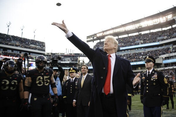 FILE - In this Dec. 8, 2018, file photo, President Donald Trump tosses the coin before the Army-Navy NCAA college football game in Philadelphia. The 120th Army-Navy game is set for Saturday in Philadelphia.  President Donald Trump will attend his second straight Army-Navy game. Presidents, by custom, sit on the Army side of the stadium for one half and the Navy side for the other. (AP Photo/Matt Rourke, File)