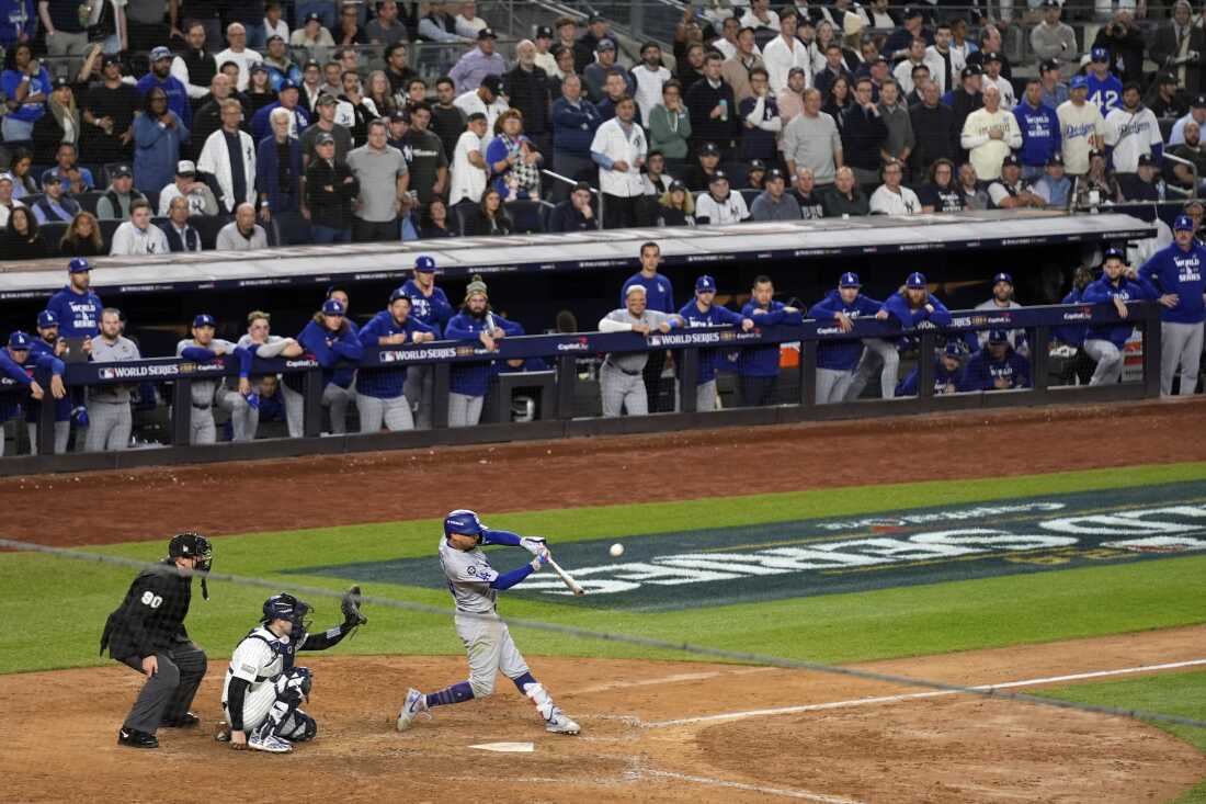 Los Angeles Dodgers' Mookie Betts, right, hits a sacrifice fly as New York Yankees catcher Austin Wells, center, reaches for the pitch during the eighth inning in Game 5 of the baseball World Series, Wednesday, Oct. 30, 2024, in New York. (AP Photo/Seth Wenig)