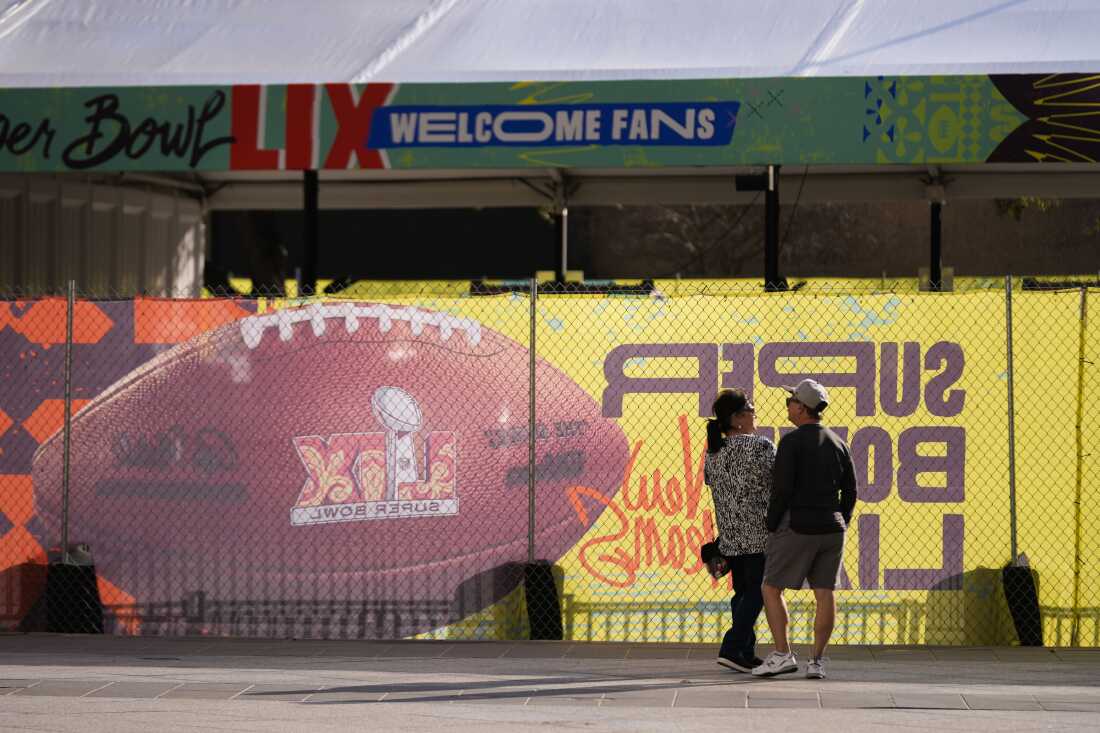 People stand outside a Super Bowl sign at the Caesars Superdome.