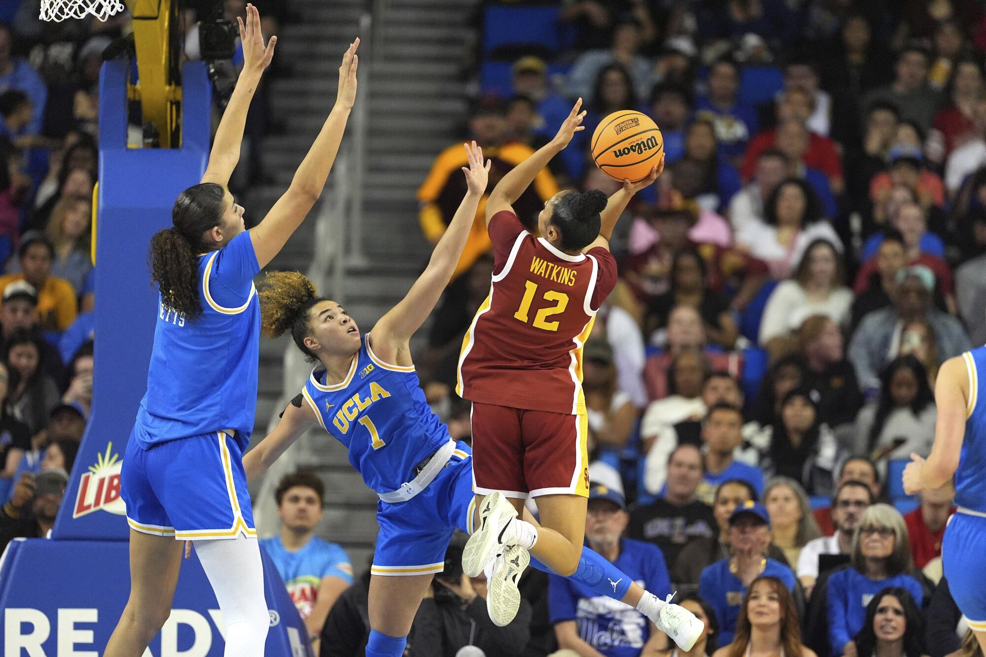 USC guard JuJu Watkins, right, shoots as UCLA center Lauren Betts, left, and guard Kiki Rice try to defend.