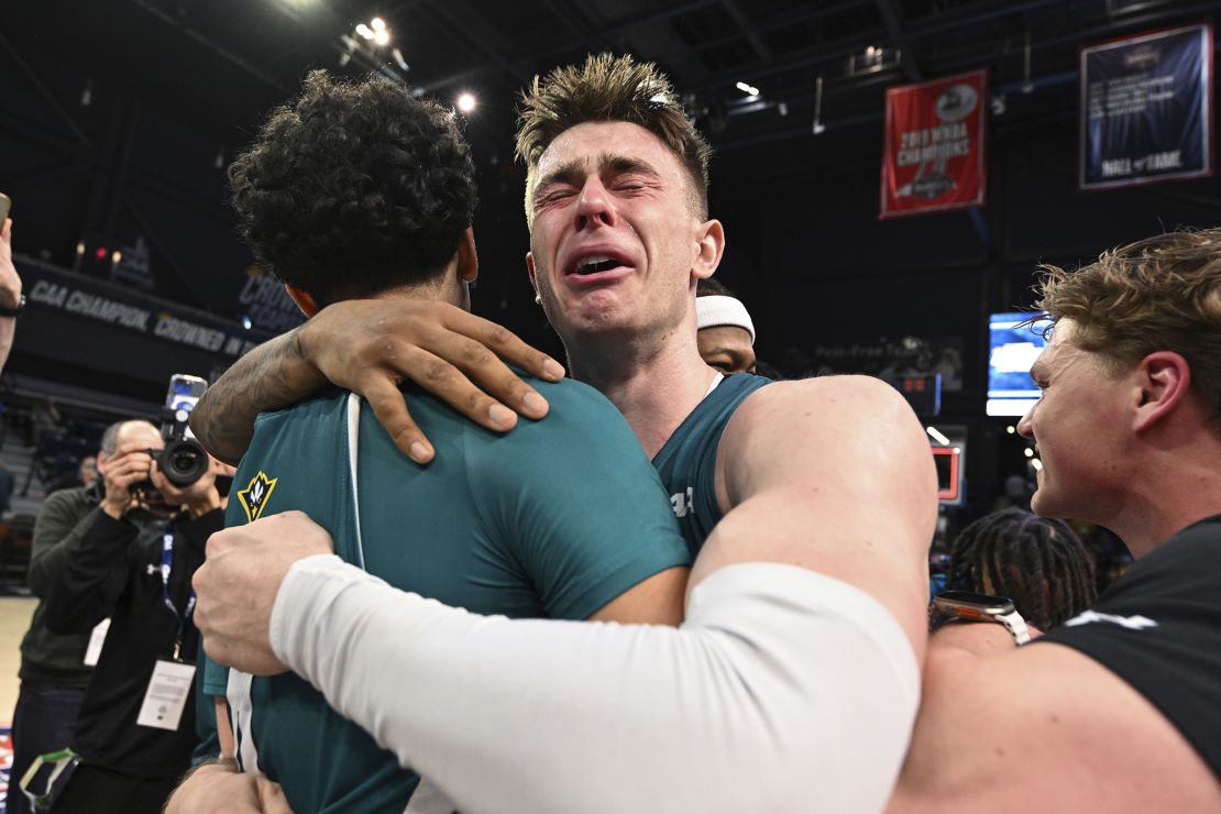 UNCW guard Noah Ross, right, hugs guard Nolan Hodge after the team won the CAA championship.