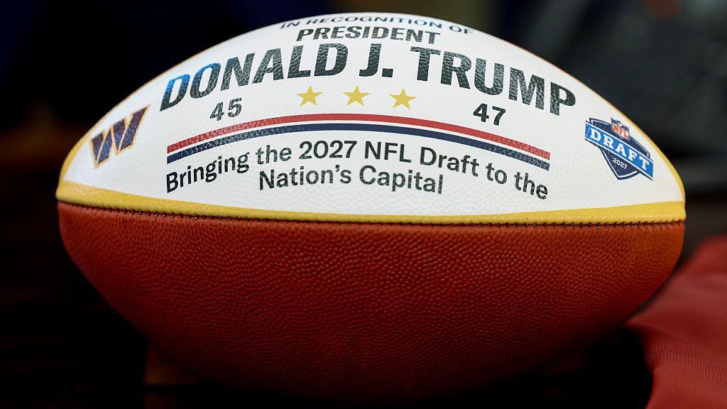An American Football with writing 'President Donald J Trump, bringing the 2027 NFL Draft to the nation's capital'.