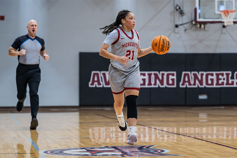 Hawkins dribbling basketball with referee and goal visible behind her
