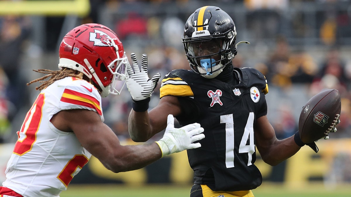 Pittsburgh Steelers wide receiver George Pickens, #14, runs after a catch as Kansas City Chiefs safety Justin Reid plays defense