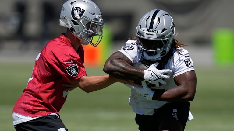 Las Vegas Raiders' quarterback Cam Miller hands off a ball...